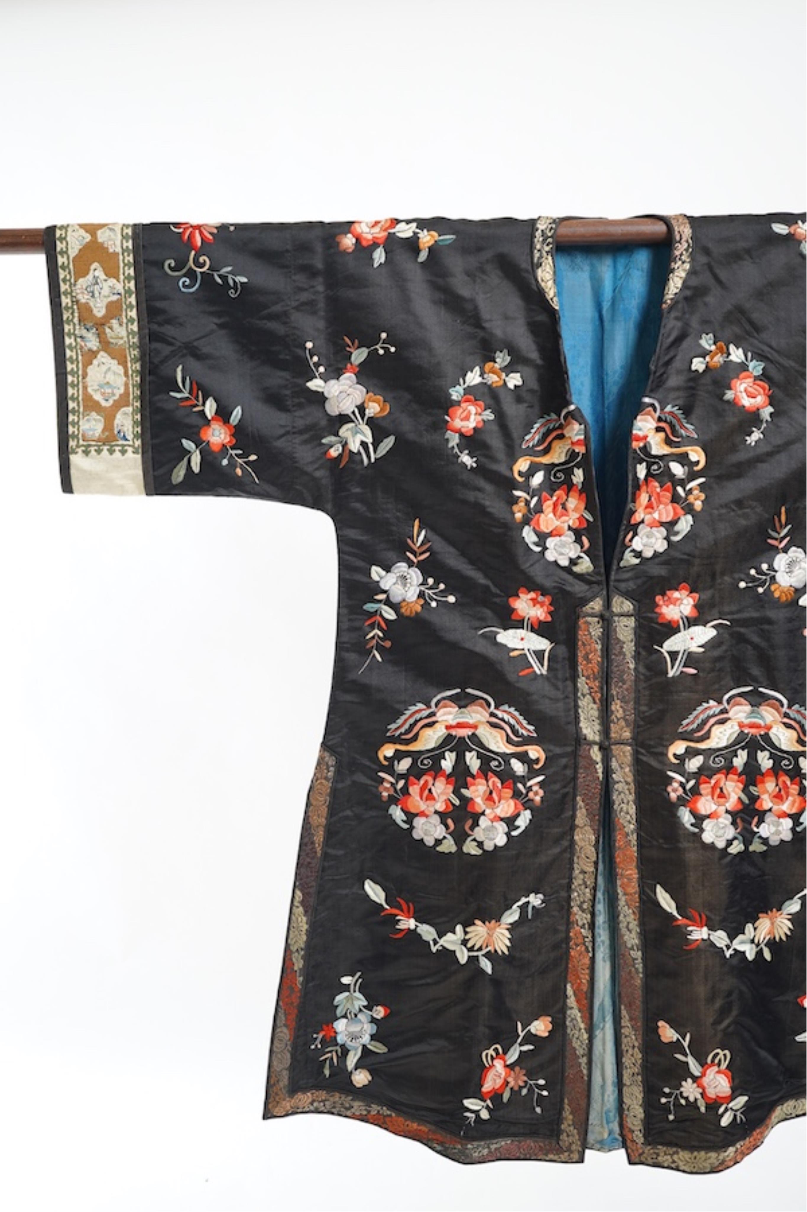 A late 19th early 20th century Chinese black silk polychrome embroidered ladies robe, decorated with cream silk, gilt and Peking knot bordered sleeve bands. The sleeve bands worked with fine figural and other embroidered